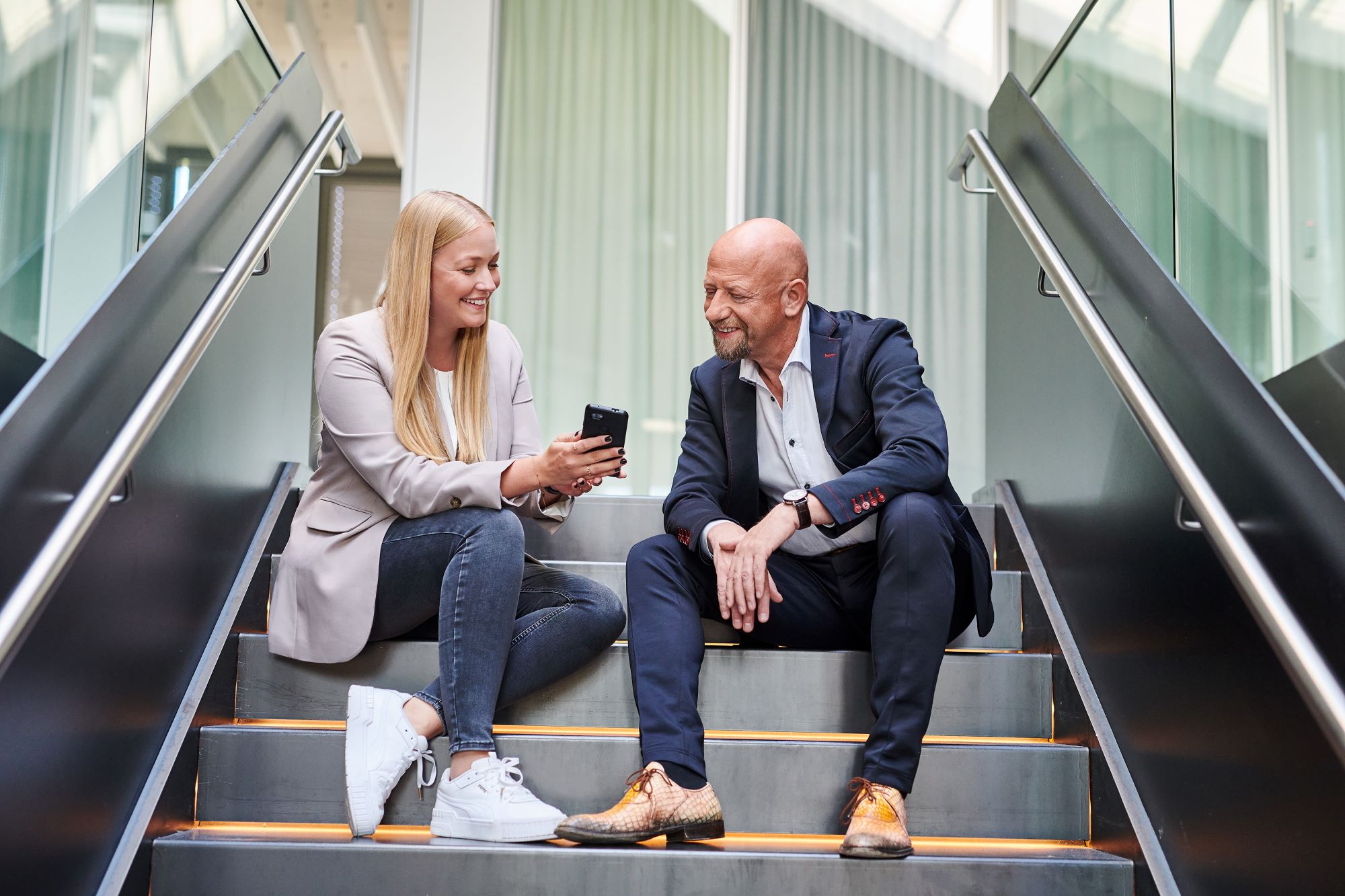A team member shares an entry-level job on her phone with a colleague.