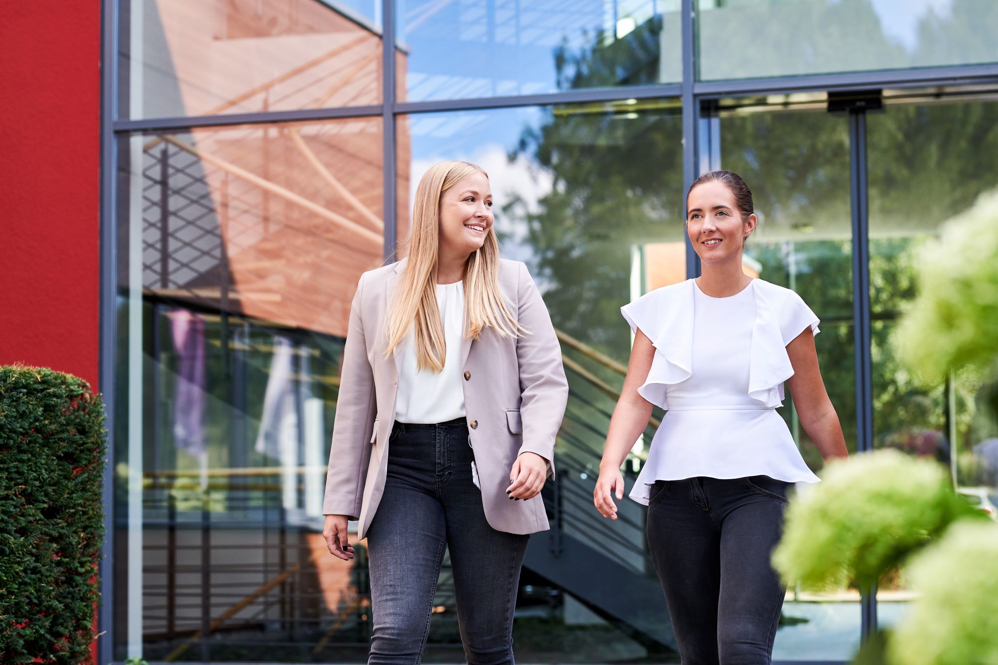 Two colleagues enjoy a walk & talk across the campus – smiling, and happy to have found their dream job at d.velop.