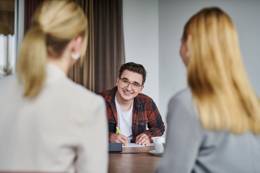 An applicant sits opposite two employees from Recruiting and smiles at them